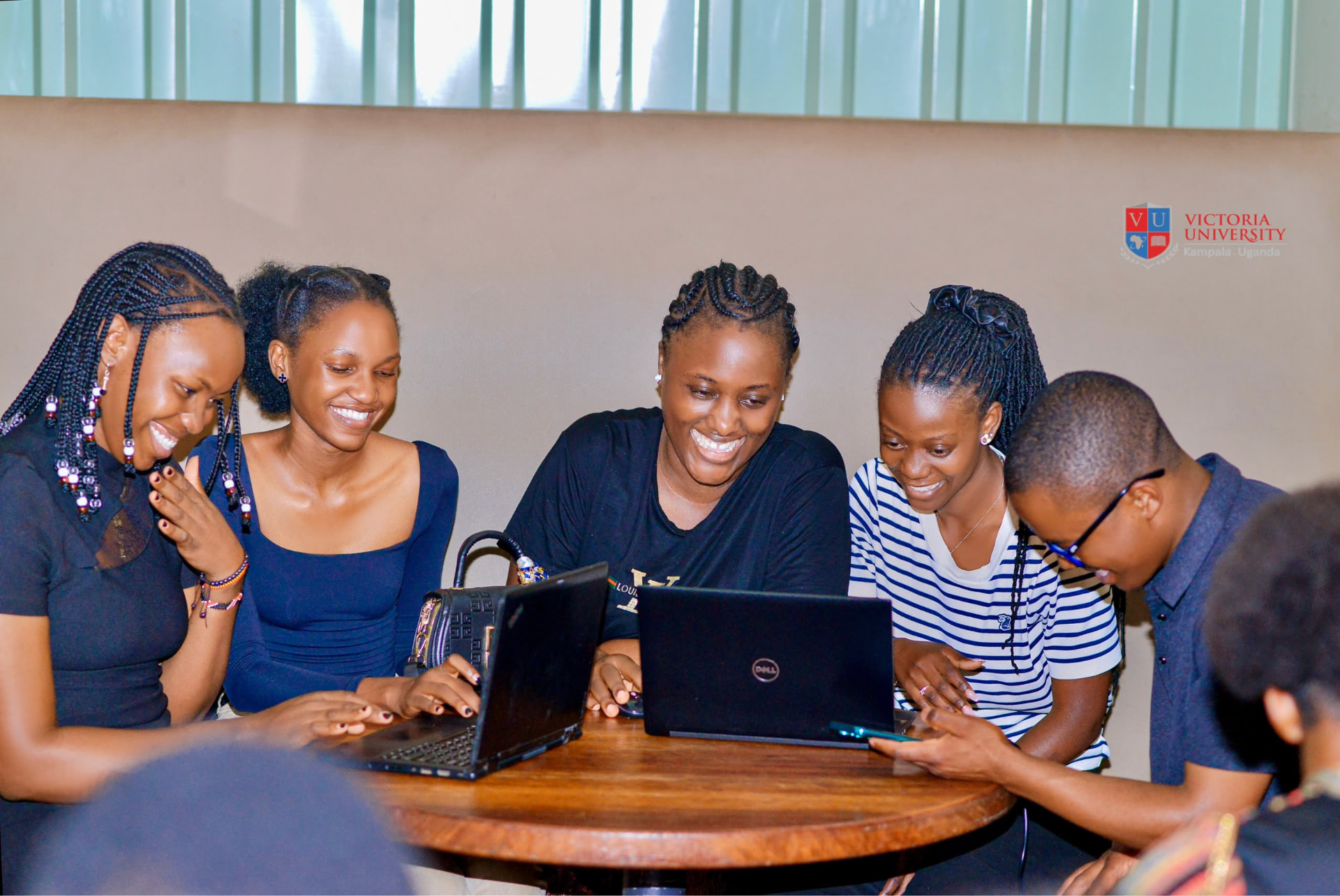 Victoria University students studying together on laptops at the Kampala campus